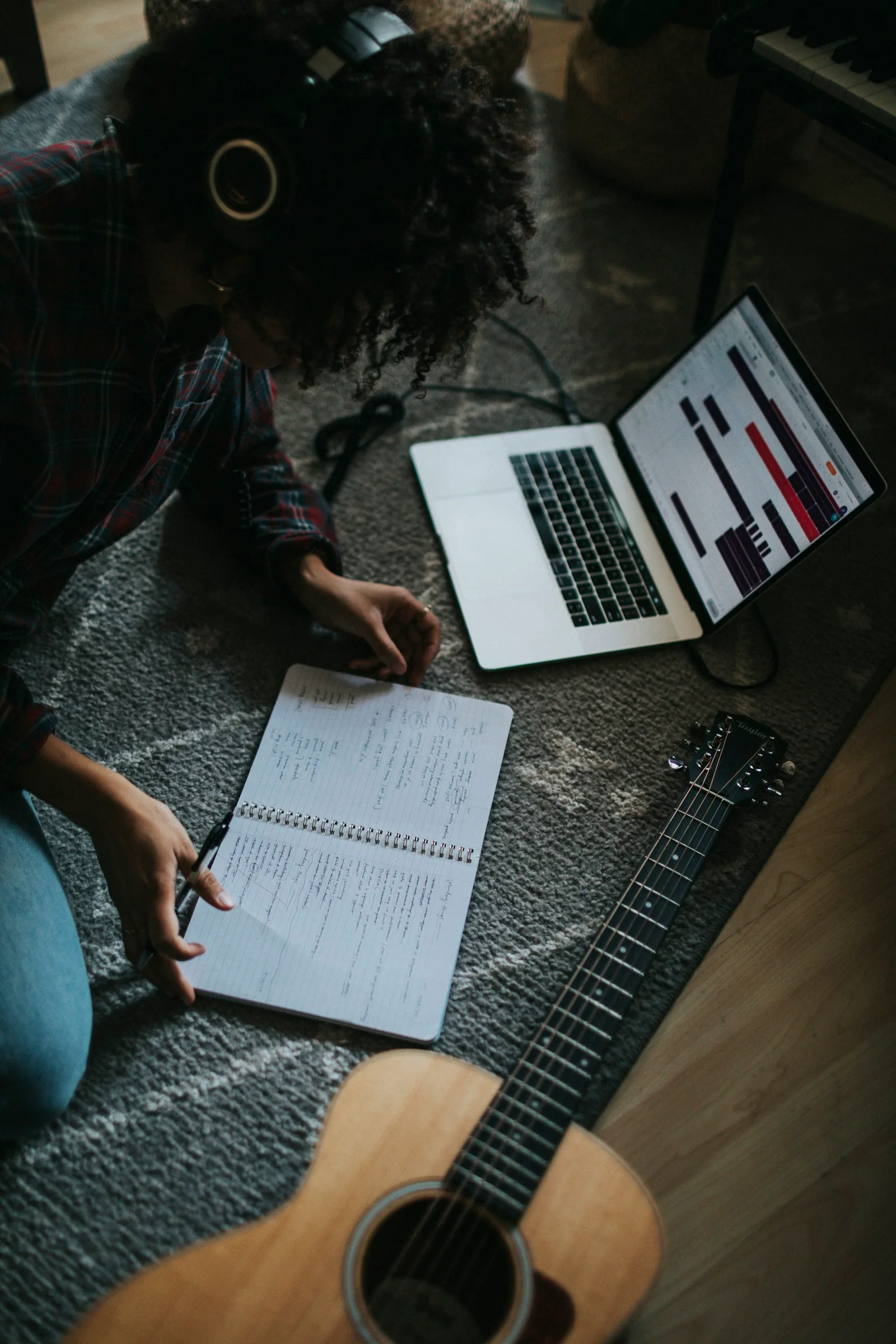Illustrative songwriting session with a notebook, guitar and laptop